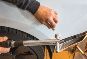 Paintless dent repair on white car fender