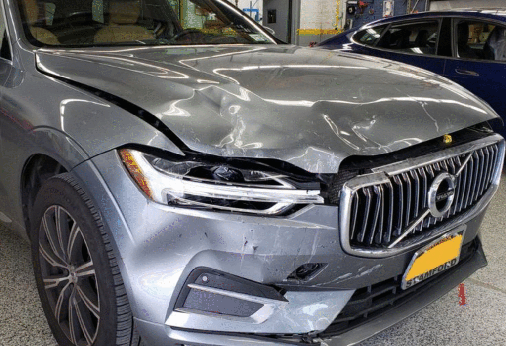 Silver Volvo SUV with front-end collision damage.