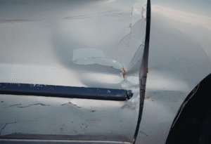 Cracked white car door with collision damage
