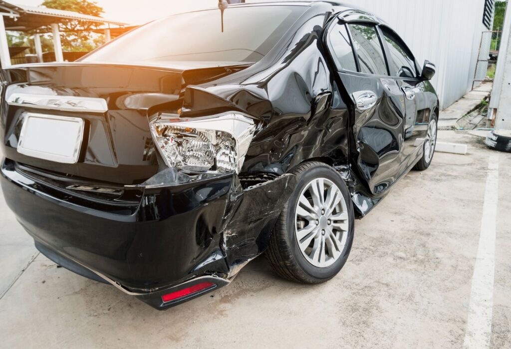 Black car with severe rear side collision damage.