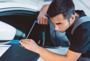 Technician cleaning a car window with a detailing tool.