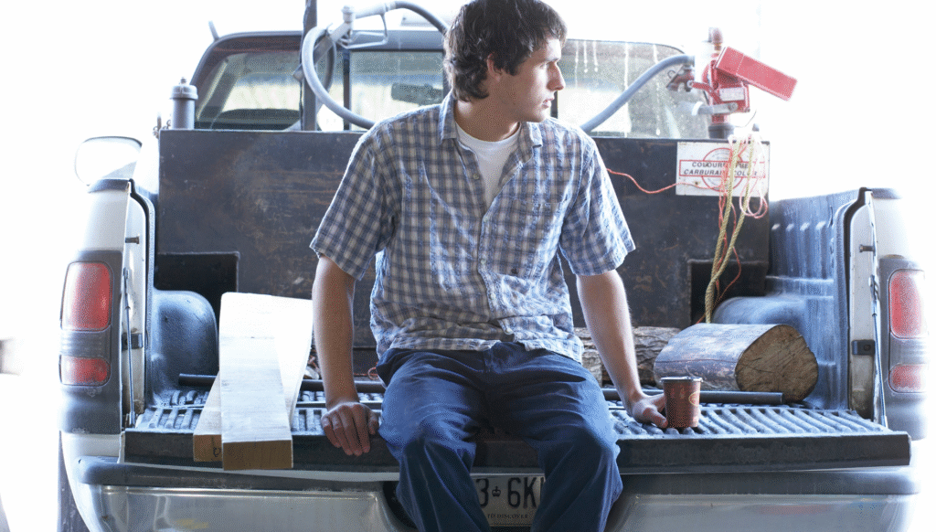 Man sitting on the open tailgate of a pickup truck.