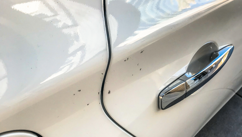 White car door with small scratches near the handle.