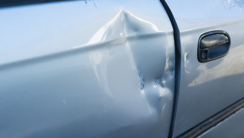 Dented silver car door with visible collision damage.