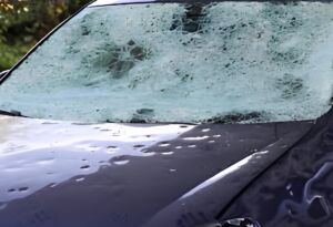 Hail-damaged car windshield covered with cracks and impact marks
