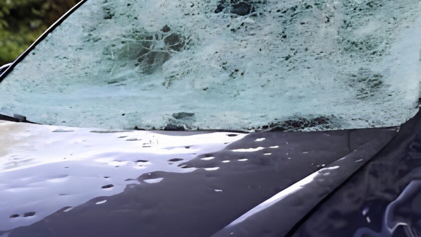 Hail-damaged car windshield covered with cracks and impact marks