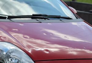 Red car hood with visible hail dents