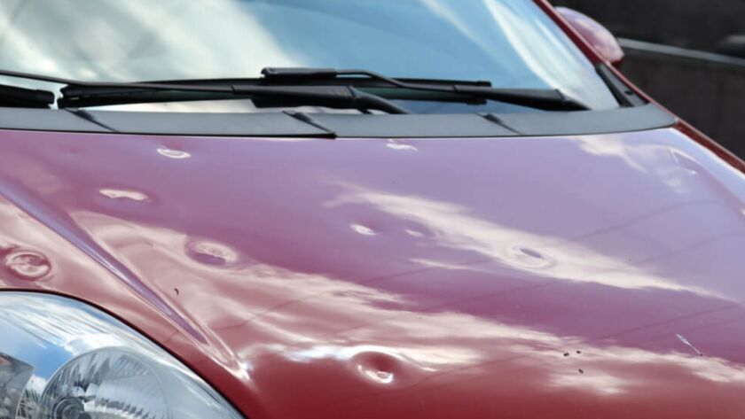 Red car hood with visible hail dents