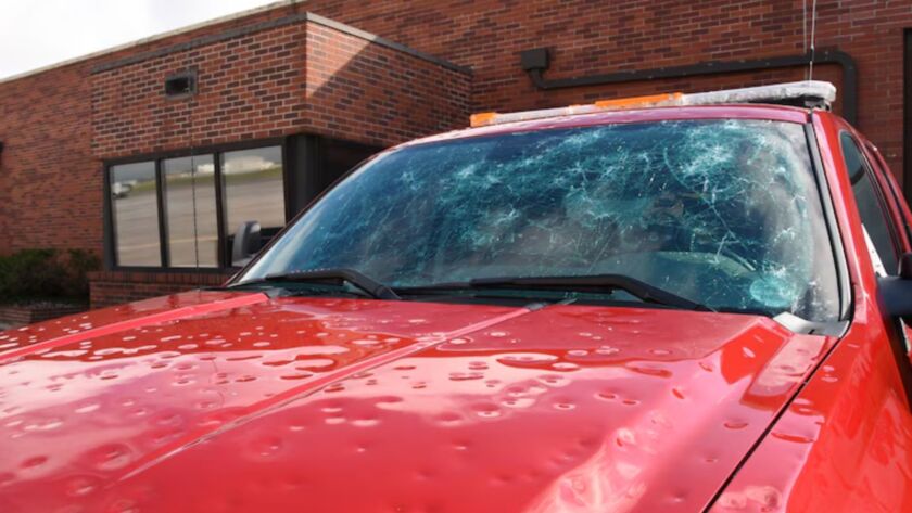 Red truck with hail dents and cracked windshield