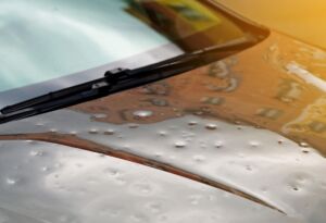 Car hood with hail dents and windshield wipers