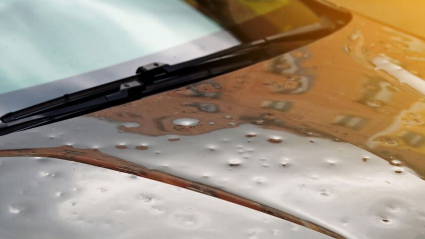 Car hood with hail dents and windshield wipers