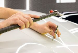 Paintless dent repair tool fixing hail damage on car roof