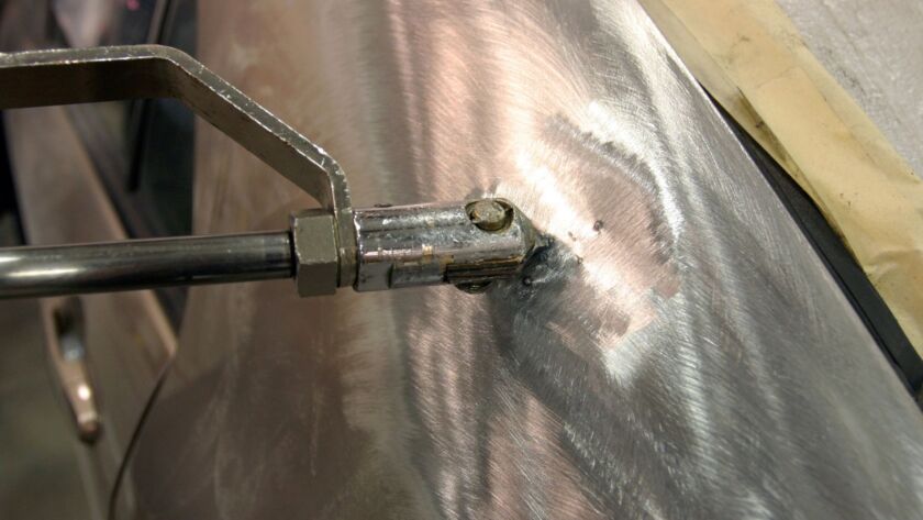 Auto body dent repair tool working on car panel