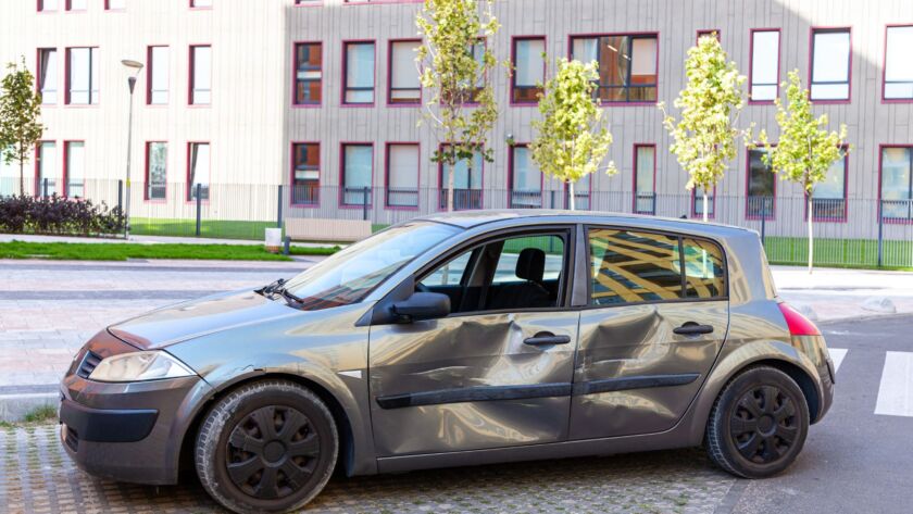 Damaged car with large dents on side doors