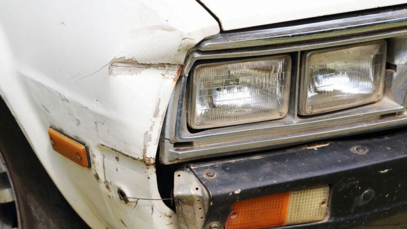 Old car front end with rust, scratches, and bumper damage