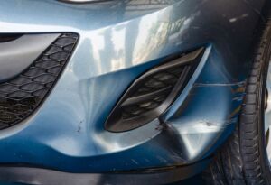 Blue car front bumper with scratches and dent damage