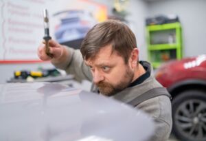 Technician inspecting car dents for paintless dent repair