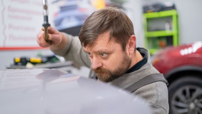 Technician inspecting car dents for paintless dent repair