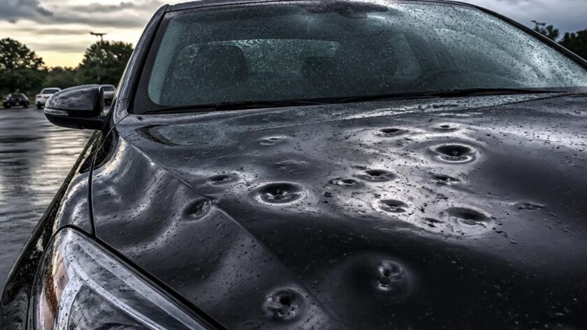 Car hood with severe hail damage after storm