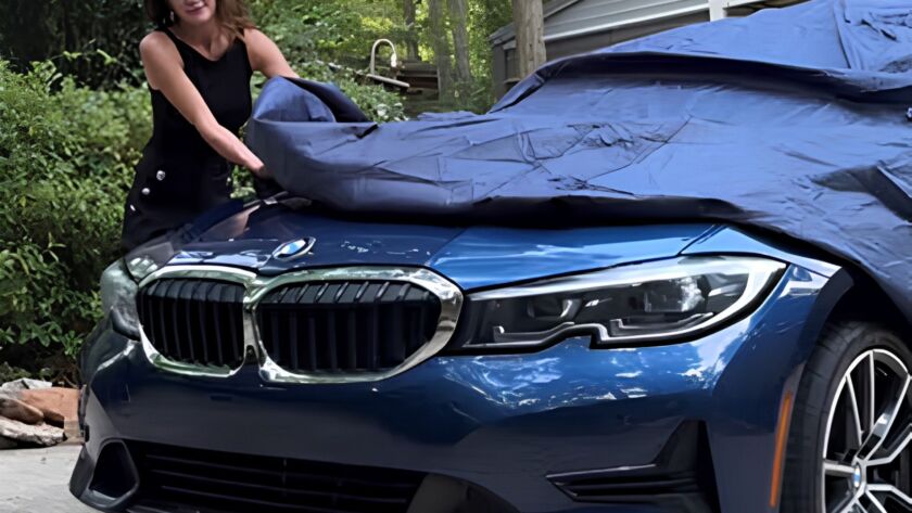 Woman covering a blue car to protect it from hail damage
